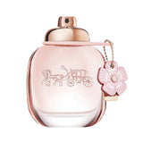 A pink Coach perfume bottle with a horse and carriage emblem and a flower charm.