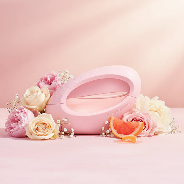 A pink, oval-shaped perfume bottle with "ariana grande" embossed on the side.